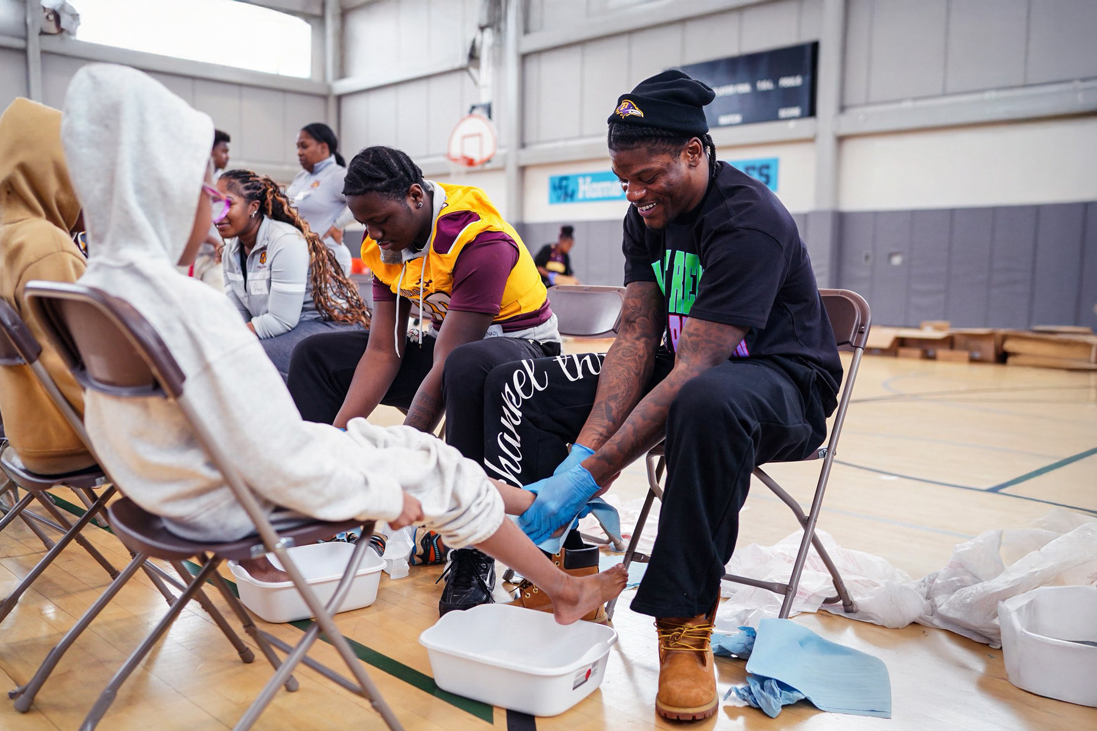 Baltimore Ravens Players Wash Local Students’ Feet and Give Them New Shoes, Led By Team Chaplain